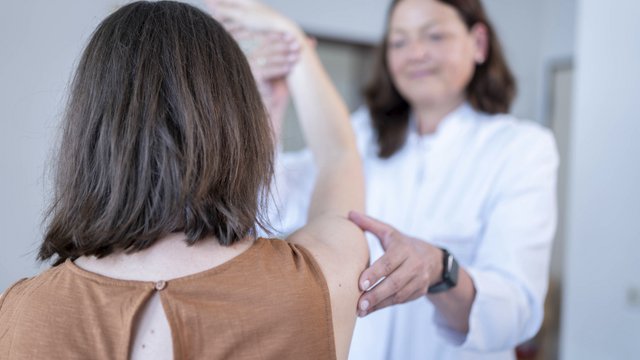 Orthopädin untersucht die Beweglichkeit der Schulter bei einer Patientin
