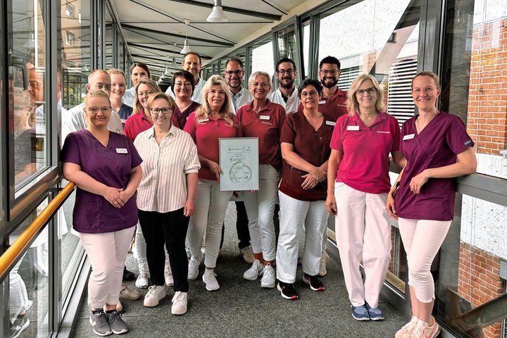 Mitarbeitende der Hunsrück Klinik stehen zusammen und halten ein Zertifikat in der Hand.