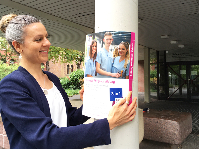 Frau hängt Plakat auf