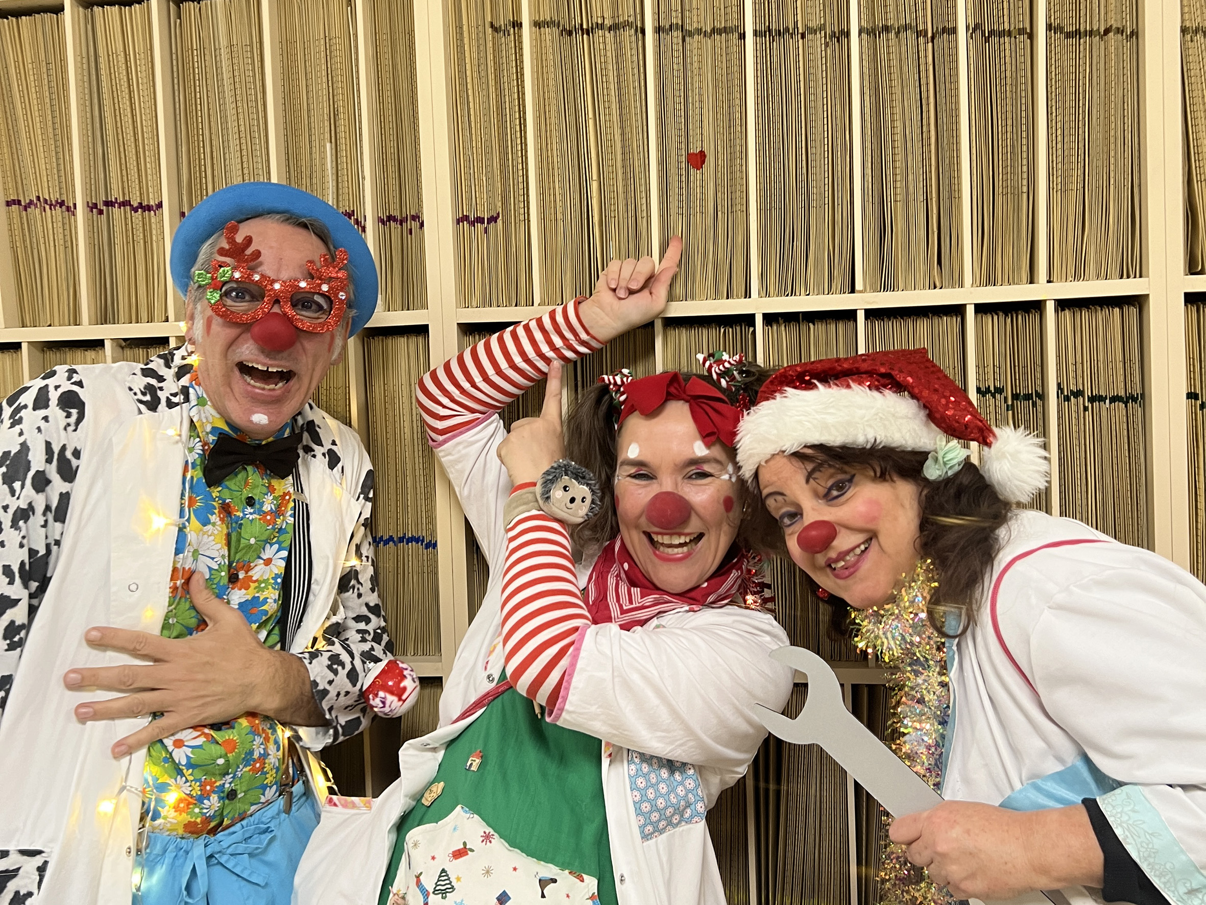 Drei Klinikclowns vor einem Regal mit Röntgenaufnahmen