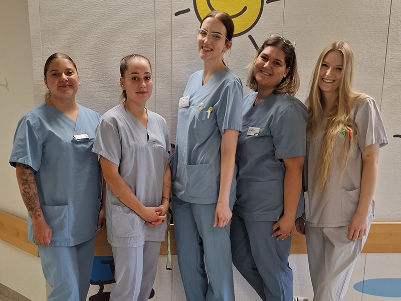 Gruppfenfoto von fünf angehenden Pflegefachpersonen auf der Kinderstation der Diakonie Kliniken