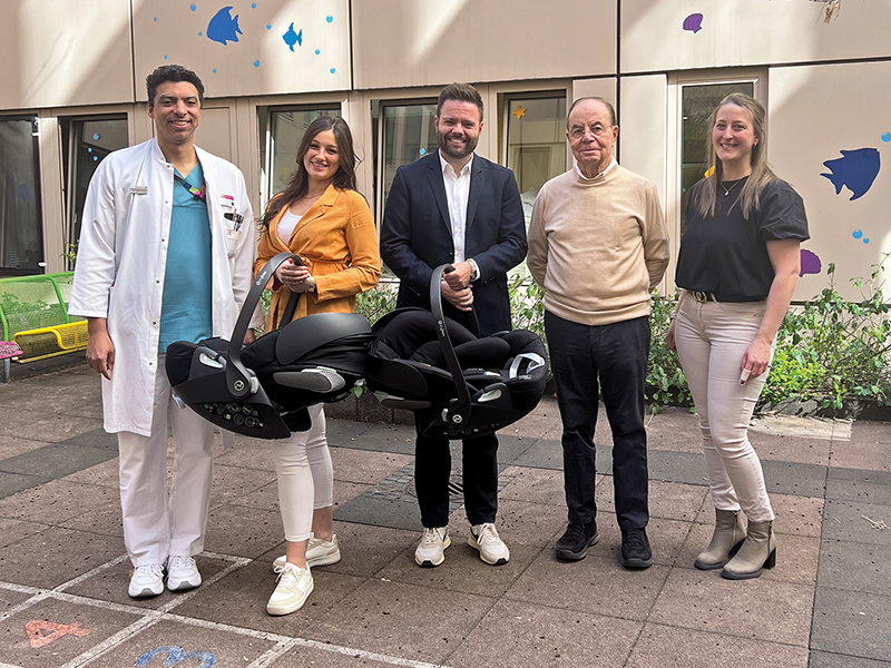 Zwei Mitarbeiter des Autohauses übergeben neue Babyschalen an Mitarbeiter der Diakonie Kliniken