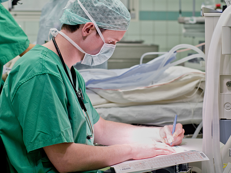 Anästhesist dokumentiert im OP die Narkose auf dem Patientenblatt