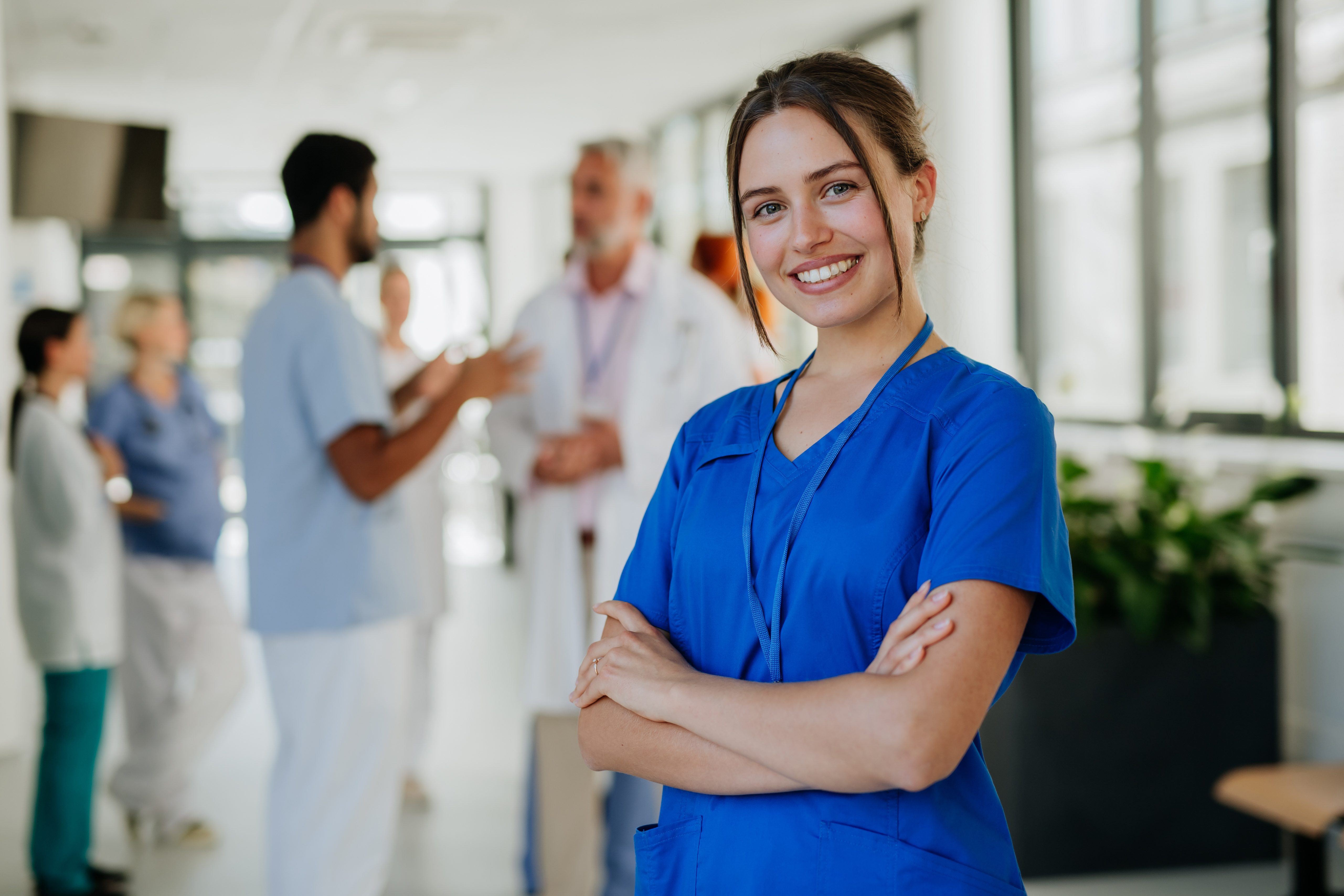 Krankenschwester steht im Gang und lacht.