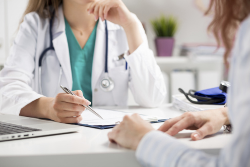 Ärztin und Patientin sitzen sich am Schreibtisch gegenüber