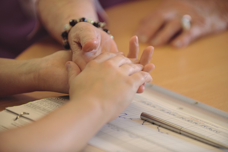 Zwei Personen halten sich an den Händen über einer Patientenakte