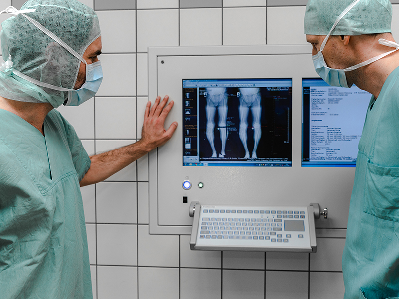 Zwei Orthopäden schauen sich im OP ein Computerbild eines Patienten an