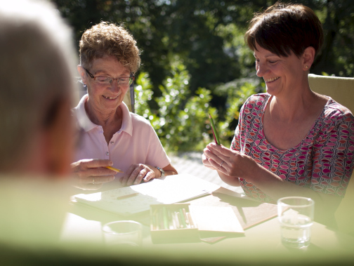 Hospizbewohner sitzen im Garten und genießen die Sonne.